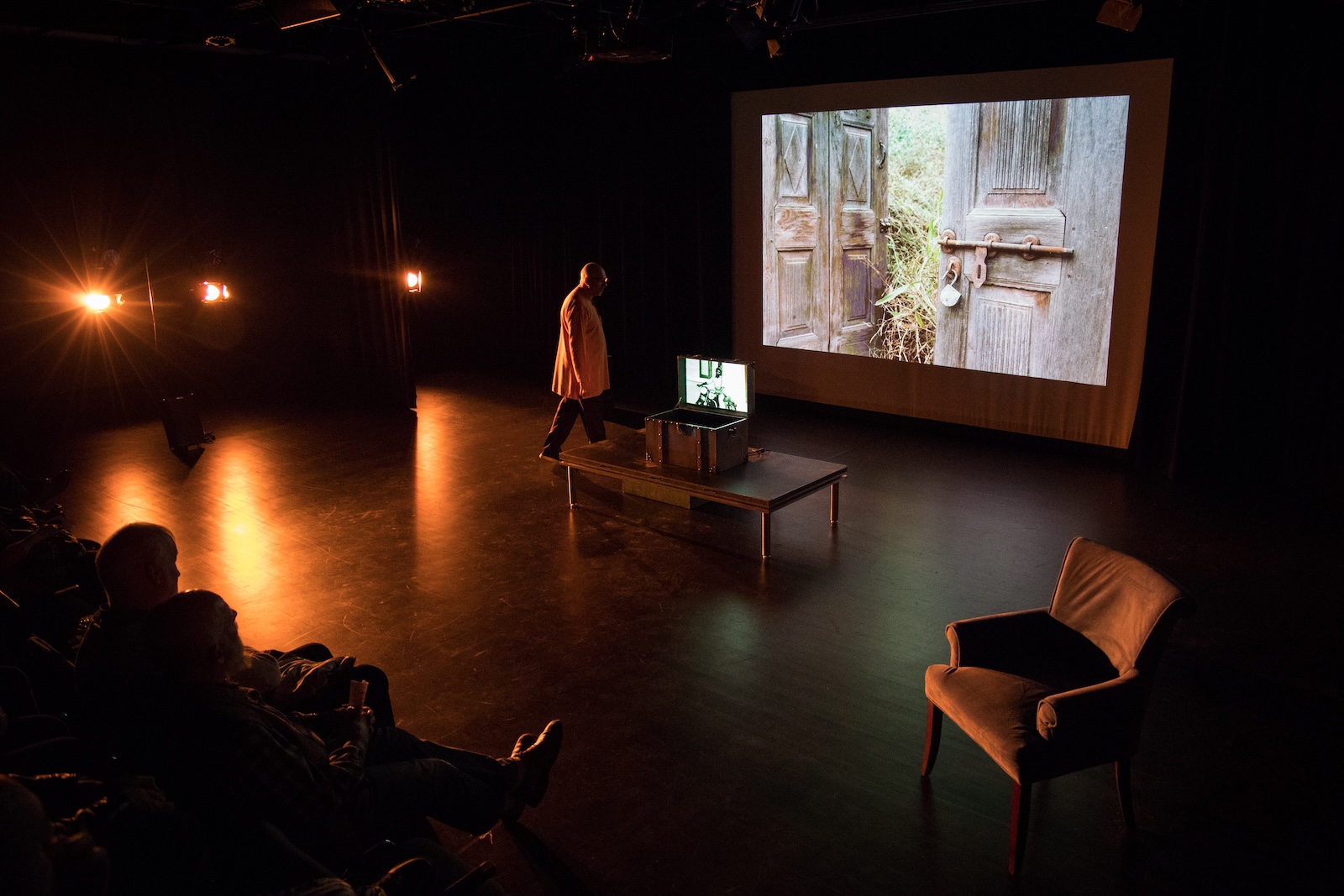 Himmat Singh Shinhat performing Panj, holding his guitar aloft with archival footage of Partition-era figures projected on the backdrop © Laurence Ly